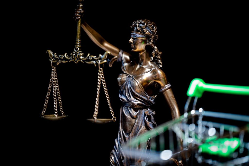 Bronze statue of Lady Justice holding balanced scales against a dark background, symbolizing law, fairness, and the legal system.