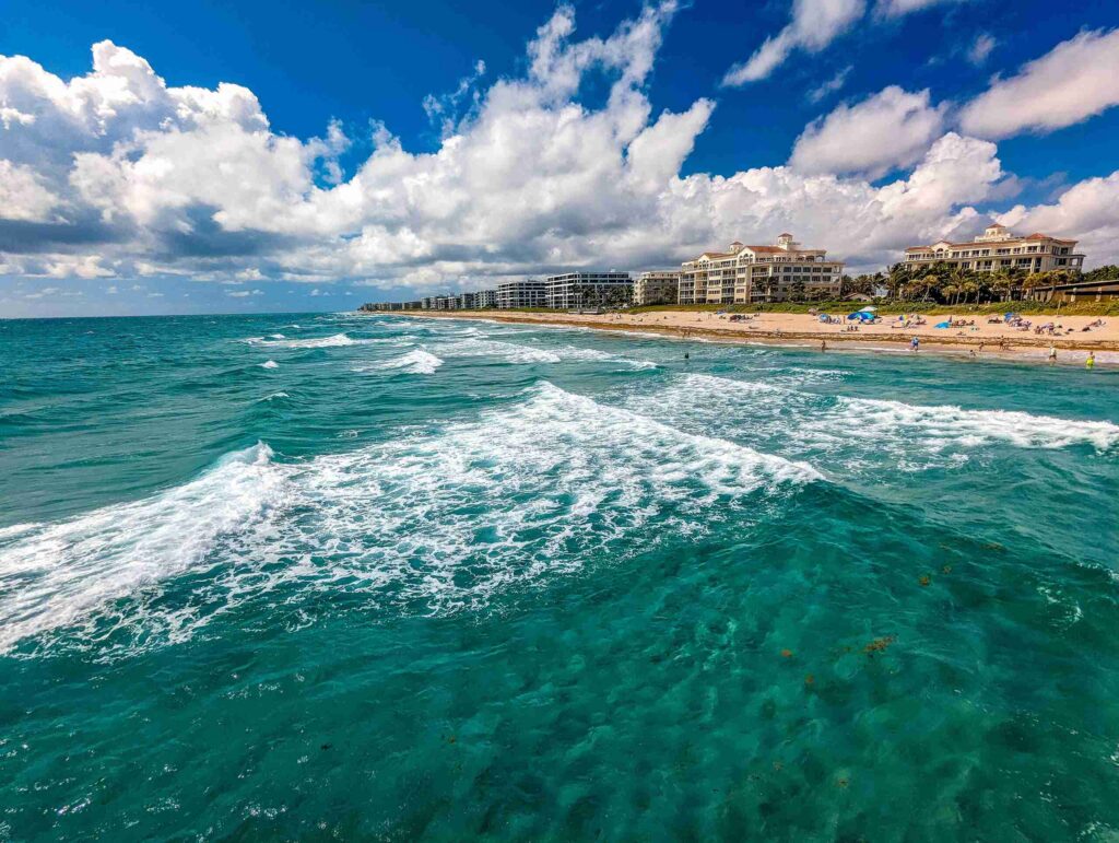 Turquoise ocean waves and a sandy beach lined with coastal buildings, representing the community served by a personal injury lawyer in Lake Worth.