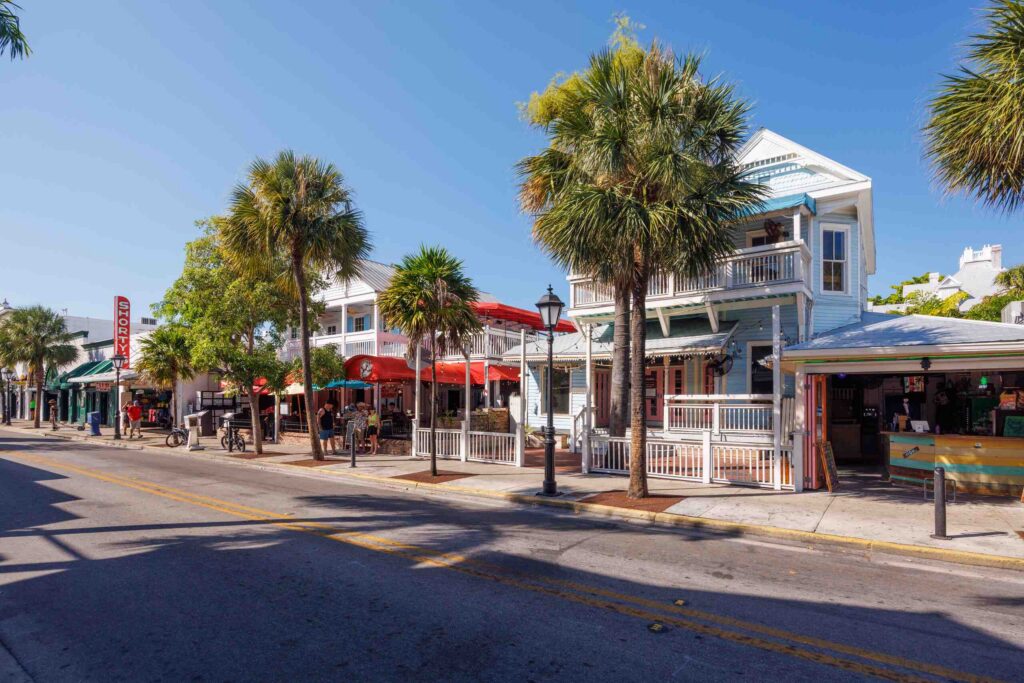 A sunny, coastal street in St. Petersburg, Florida, lined with palm trees, historic two-story buildings, and outdoor restaurant patios under a clear blue sky, indicating the region served by St. Petersburg personal injury attorneys.