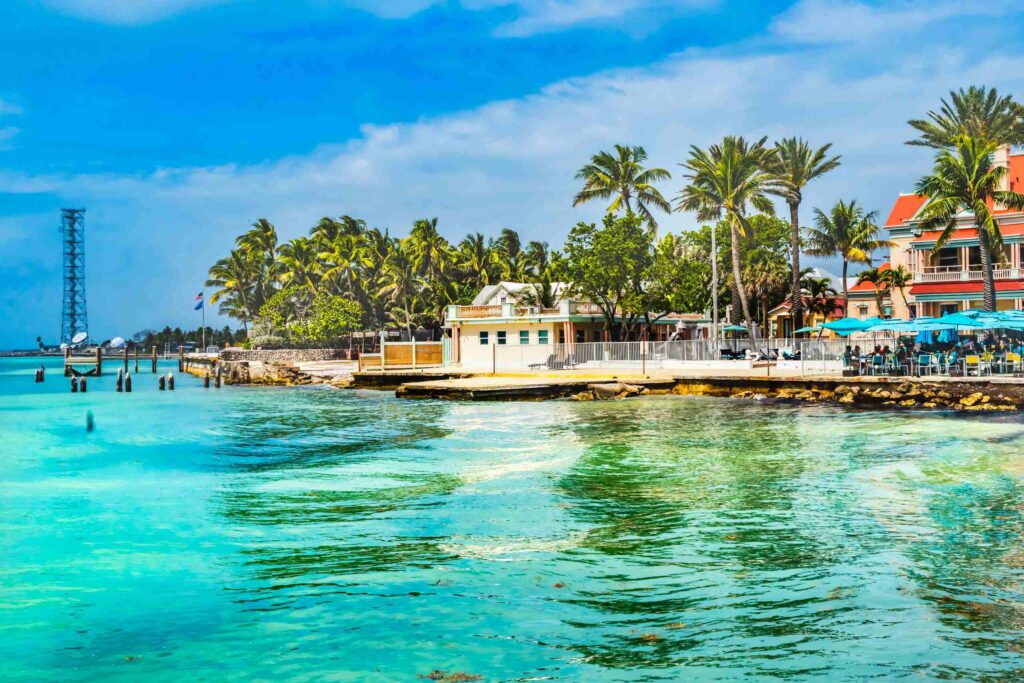 A scenic coastal view featuring turquoise water, palm trees, and waterfront buildings under a bright blue sky, representing the geographic region served by Stuart & Treasure Coast personal injury attorneys.