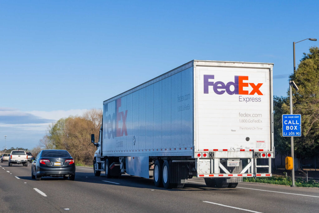 A FedEx Express semi truck driving on a highway representing cases handled by West Palm Beach FedEx Truck Accident Lawyers.