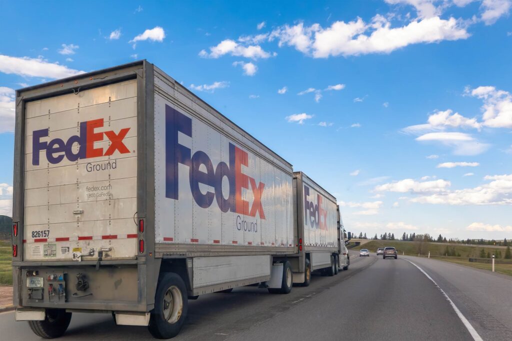 A large FedEx Ground semi truck driving on a highway explaining who is liable when a FedEx truck hits you in Florida.