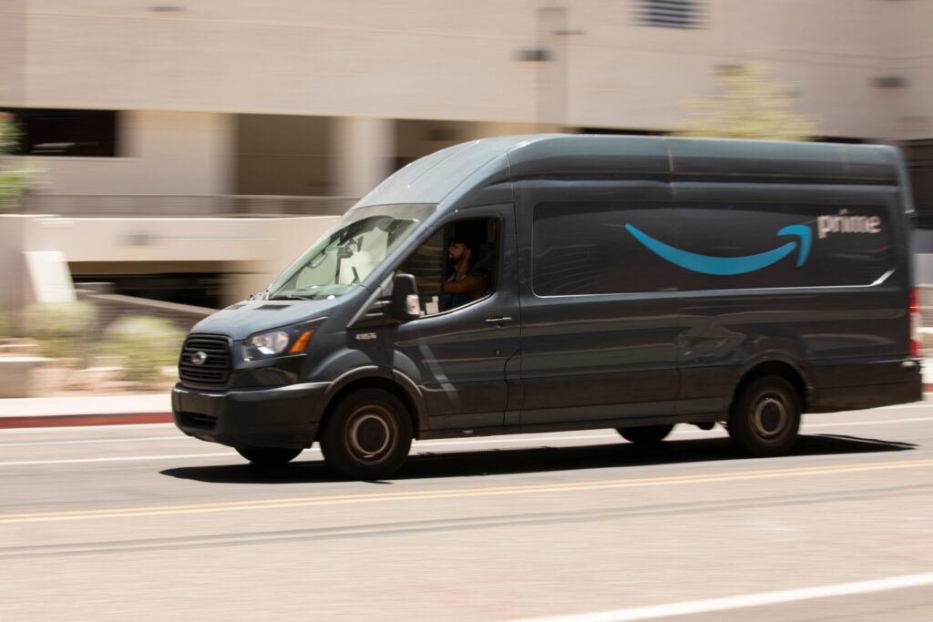Grey Amazon Prime delivery van driving through city streets explaining an Amazon delivery accident lawsuit in Florida what you need to know.