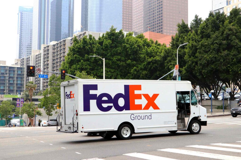 FedEx Ground delivery truck driving through a city intersection for FedEx independent contractors and workers' comp in Florida.