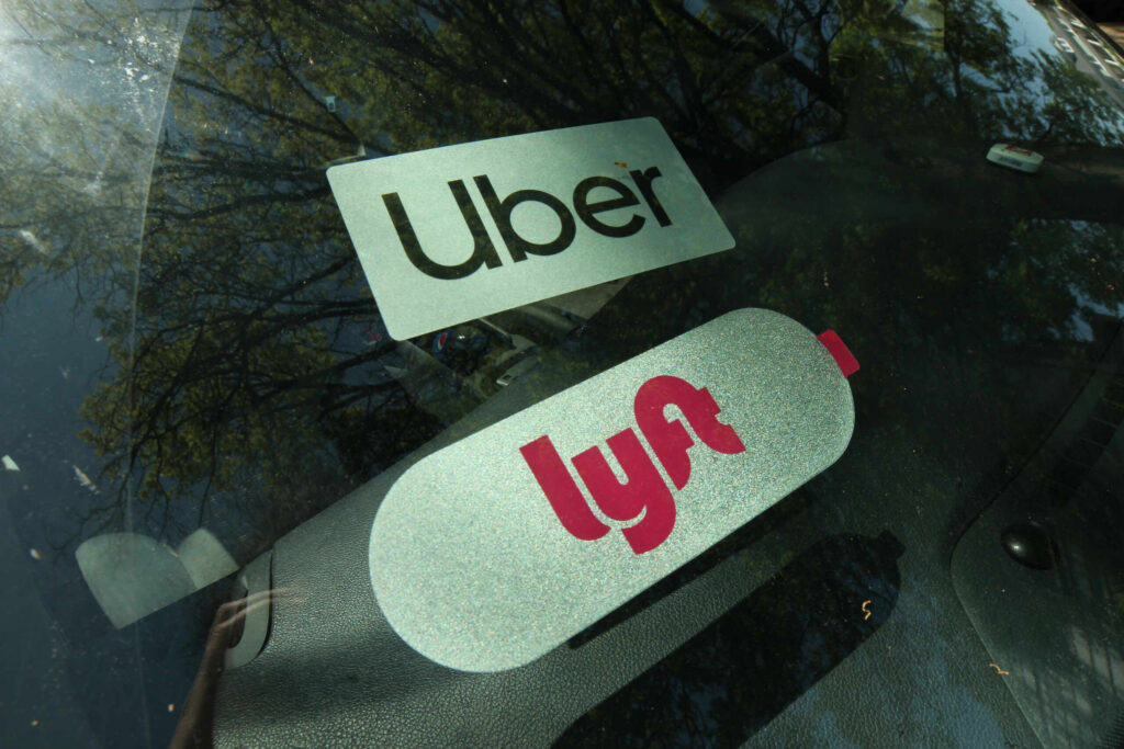 Uber and Lyft decals displayed on a car windshield questioning how much is an Uber or Lyft accident settlement worth in Florida.